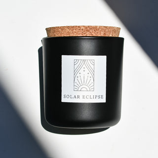 Solar Eclipse candle in black apothecary glass with cork top.