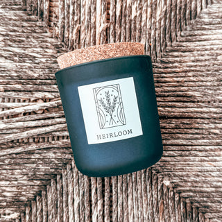 frosted blue tumbler candle with cork top with a graphic art label titled heirloom