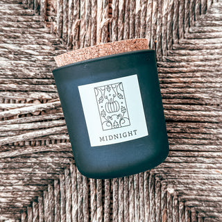 frosted blue tumbler candle with cork top and graphic label with pumpkin art titled midnight